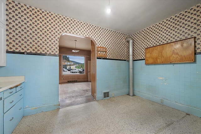 308 Main St, Deadwood, SD 57732 - bathroom featuring wallpapered walls, tile walls, wainscoting, and speckle patterned floor
