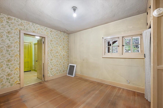 308 Main St, Deadwood, SD 57732 - spare room with hardwood / wood-style flooring, baseboards, wallpapered walls, and a textured ceiling