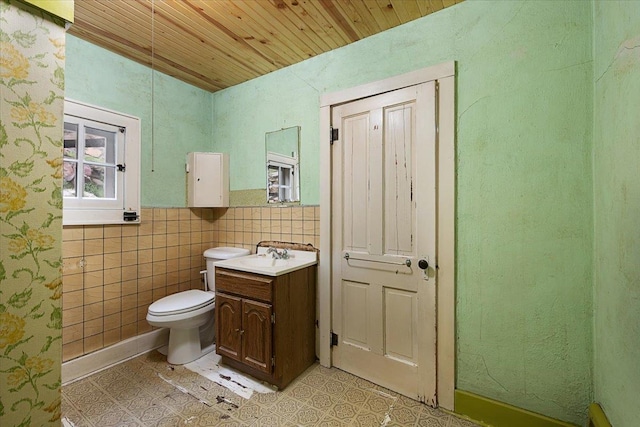 308 Main St, Deadwood, SD 57732 - bathroom with wood ceiling, toilet, vanity, tile walls, and wainscoting
