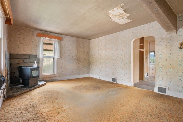 308 Main St, Deadwood, SD 57732 - unfurnished living room with a wood stove, arched walkways, carpet floors, and baseboards