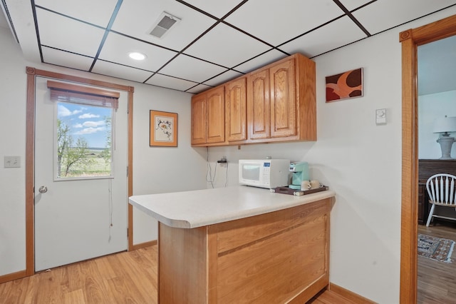 18977 Black Angus Ln, Belle Fourche, SD 57717 - kitchen featuring white microwave, light wood finished floors, a peninsula, light countertops, and baseboards