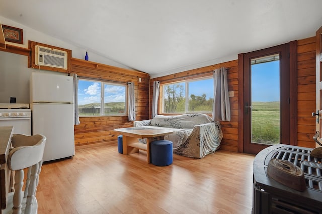18977 Black Angus Ln, Belle Fourche, SD 57717 - bedroom with freestanding refrigerator, vaulted ceiling, multiple windows, light wood-type flooring, and wooden walls