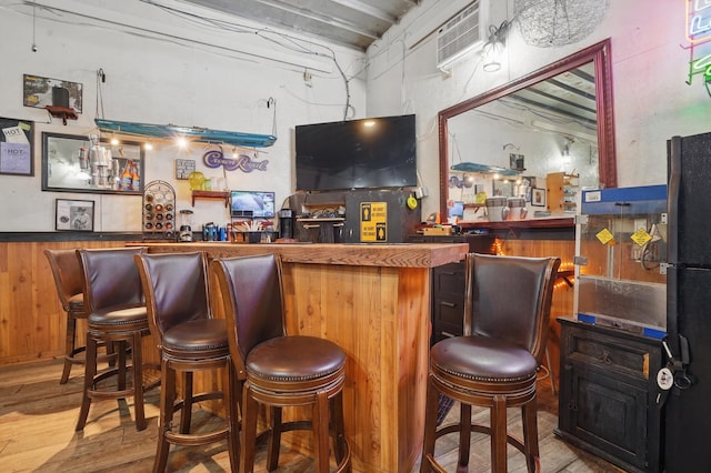 18977 Black Angus Ln, Belle Fourche, SD 57717 - indoor dry bar featuring wood finished floors, freestanding refrigerator, and an AC wall unit