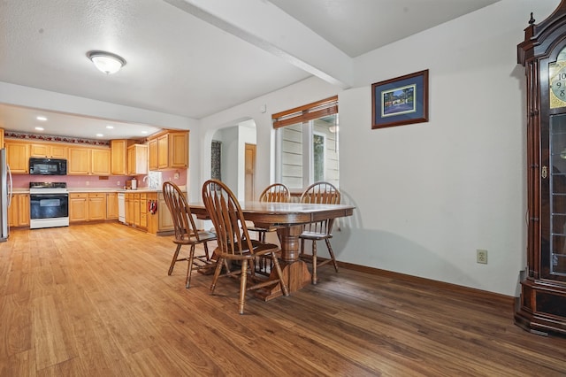 18977 Black Angus Ln, Belle Fourche, SD 57717 - dining space with light wood finished floors, arched walkways, baseboards, and recessed lighting