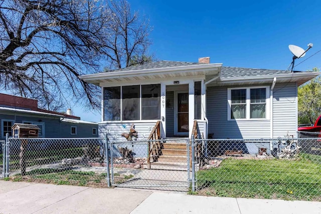 1007 Elkhorn St, Belle Fourche, SD 57717 - view of front facade with a gate, roof with shingles, a chimney, and a sunroom