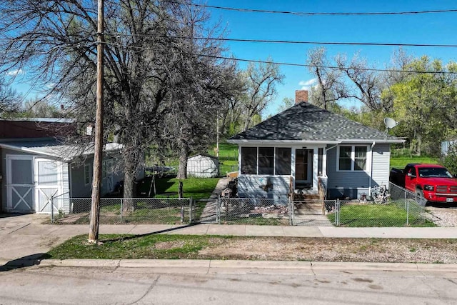 1007 Elkhorn St, Belle Fourche, SD 57717 - bungalow with a fenced front yard, a chimney, a shingled roof, an outbuilding, and a gate