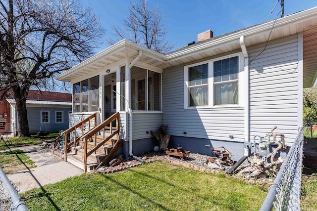 1007 Elkhorn St, Belle Fourche, SD 57717 - view of front facade with a chimney, a sunroom, and a front yard