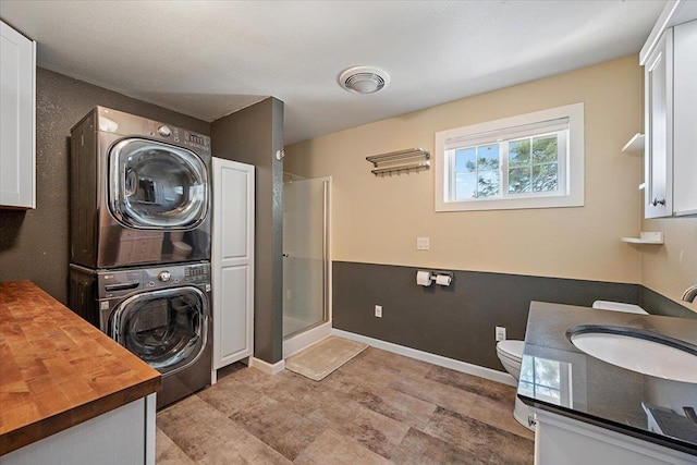 2921 1st Ave, Sturgis, SD 57785 - laundry room featuring stacked washer / dryer, a sink, and baseboards
