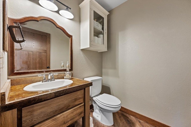 10226 Buena Vista Ln, Belle Fourche, SD 57717 - half bathroom with baseboards, wood finished floors, toilet, vanity, and a textured wall