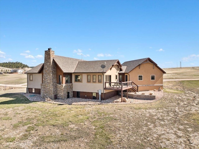 10226 Buena Vista Ln, Belle Fourche, SD 57717 - back of house with a chimney, stucco siding, roof with shingles, and a wooden deck