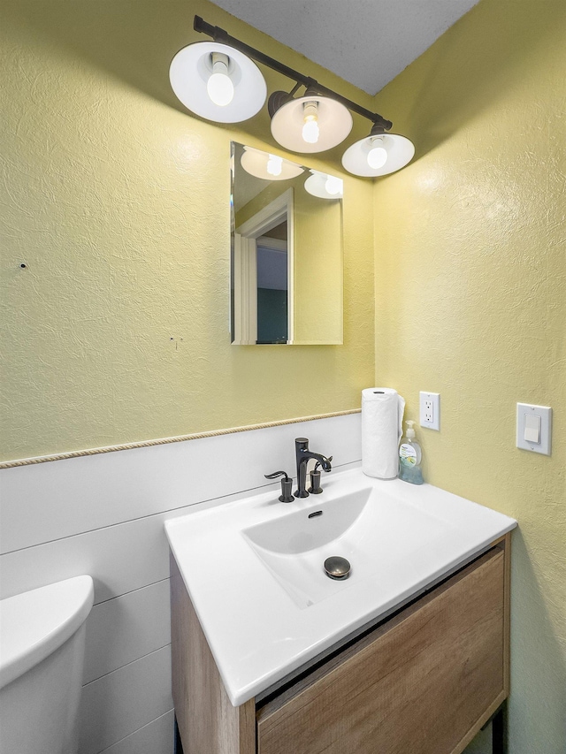 3520 Arizona St, Rapid City, SD 57701 - half bath featuring vanity, toilet, a wainscoted wall, and a textured wall