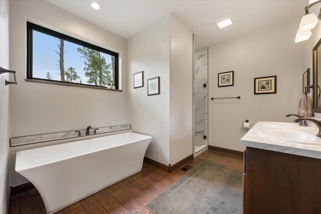 11132 Bogey Cir, Lead, SD 57754 - bathroom featuring hardwood / wood-style floors, double vanity, a freestanding bath, walk in shower, and baseboards