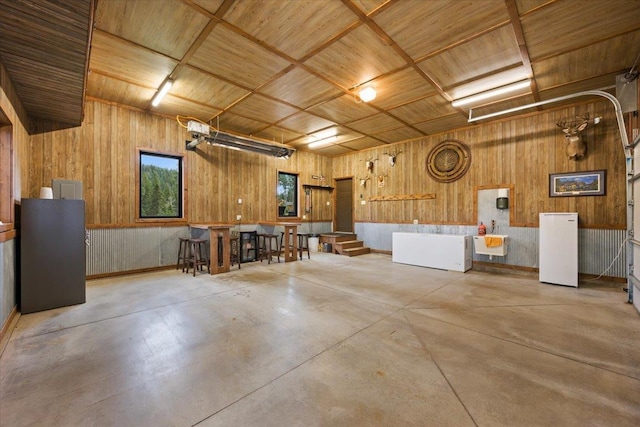 11132 Bogey Cir, Lead, SD 57754 - garage featuring freestanding refrigerator, wooden walls, and wood ceiling