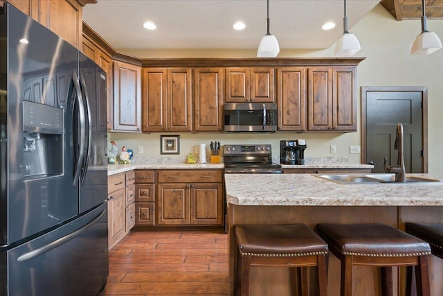 11132 Bogey Cir, Lead, SD 57754 - kitchen with stainless steel appliances, a breakfast bar area, dark wood-type flooring, hanging light fixtures, and a sink