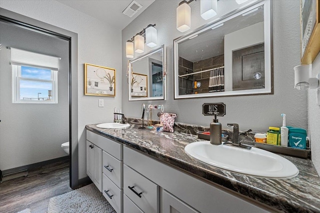 1430 Dacar St, Belle Fourche, SD 57717 - bathroom with wood finished floors, toilet, tiled shower, double vanity, and baseboards