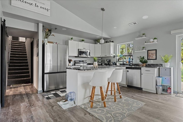 1430 Dacar St, Belle Fourche, SD 57717 - kitchen featuring stainless steel appliances, lofted ceiling, wood finished floors, white cabinets, and a kitchen bar