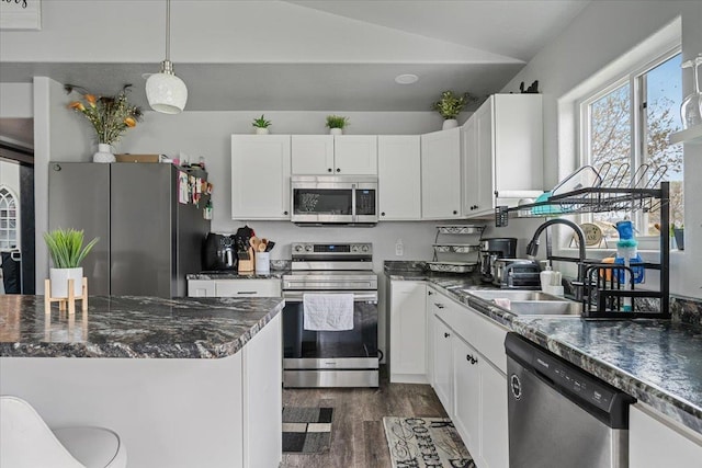 1430 Dacar St, Belle Fourche, SD 57717 - kitchen featuring appliances with stainless steel finishes, a sink, dark wood-style flooring, white cabinets, and vaulted ceiling