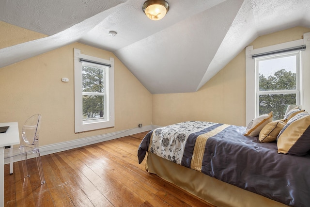 211 Milliken St, Lead, SD 57754 - bedroom featuring a textured ceiling, vaulted ceiling, baseboards, and wood-type flooring