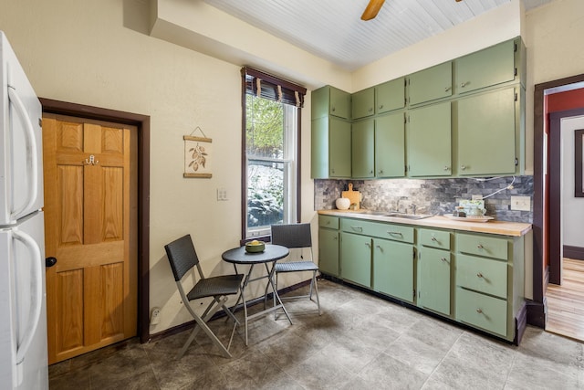 211 Milliken St, Lead, SD 57754 - kitchen with freestanding refrigerator, green cabinets, tasteful backsplash, a sink, and light countertops