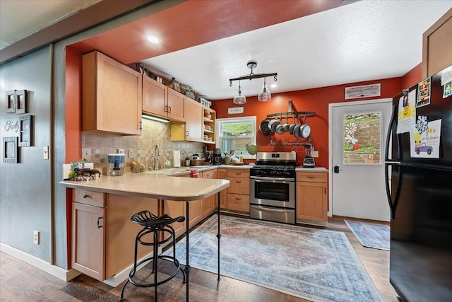 30 Adams St, Deadwood, SD 57732 - kitchen featuring gas range, freestanding refrigerator, a peninsula, light countertops, and backsplash
