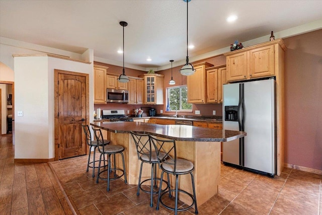 2315 Palisades Loop, Sturgis, SD 57785 - kitchen featuring appliances with stainless steel finishes, a center island, a kitchen bar, dark countertops, and light brown cabinetry
