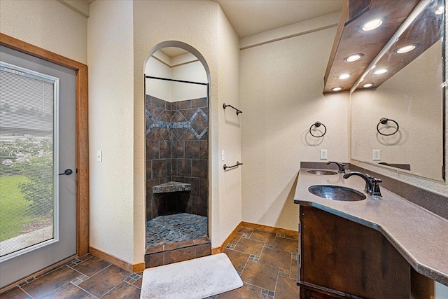 2315 Palisades Loop, Sturgis, SD 57785 - bathroom with stone tile flooring, baseboards, walk in shower, double vanity, and a textured wall