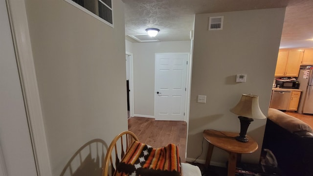 102 10th Ave, Belle Fourche, SD 57717 - hallway with a textured ceiling, light wood finished floors, and baseboards