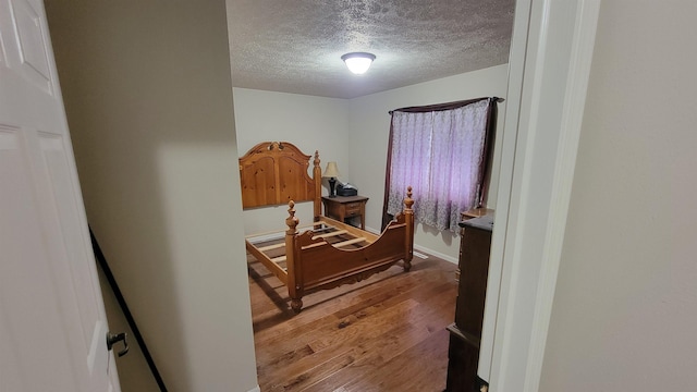 102 10th Ave, Belle Fourche, SD 57717 - bedroom with wood finished floors, a textured ceiling, and baseboards