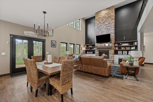 3135 American Eagle Rd, Spearfish, SD 57783 - dining area with a chandelier, light wood finished floors, a towering ceiling, a fireplace, and baseboards