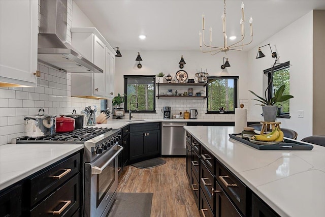 3135 American Eagle Rd, Spearfish, SD 57783 - kitchen featuring appliances with stainless steel finishes, wall chimney exhaust hood, a sink, white cabinets, and wood finished floors