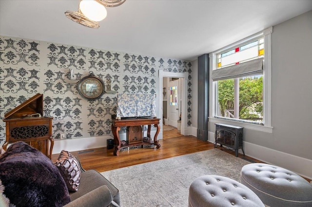 1231/2 Stone St, Lead, SD 57754 - living room featuring wallpapered walls, a wood stove, wood finished floors, baseboards, and heating unit