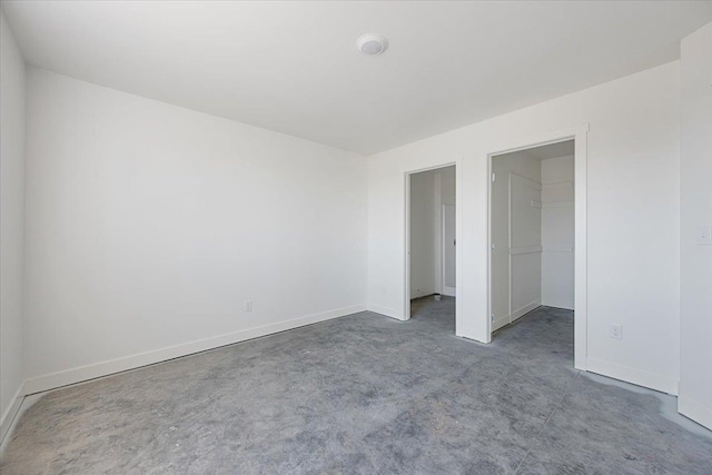 10884 Eagle Ct, Belle Fourche, SD 57717 - unfurnished bedroom with a walk in closet, baseboards, a closet, and carpet flooring