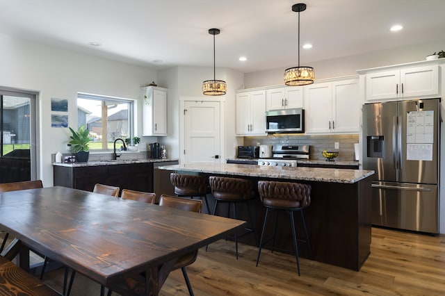 2259 Suntory Ave, Spearfish, SD 57783 - kitchen featuring stainless steel appliances, a center island, white cabinets, tasteful backsplash, and wood finished floors