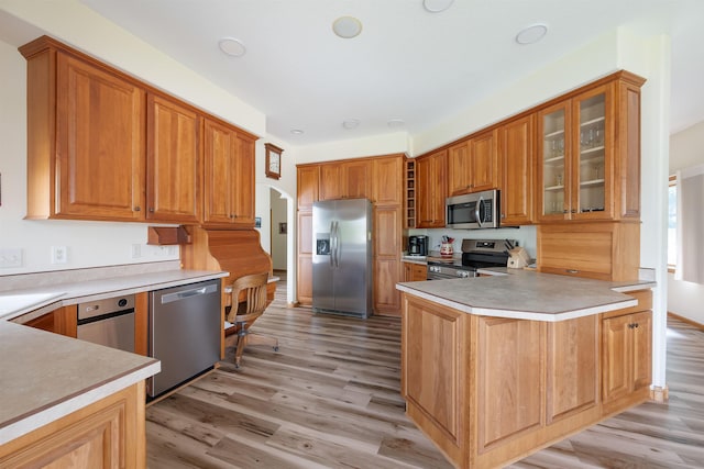 2340 Camaro Cir, Sturgis, SD 57785 - kitchen with stainless steel appliances, a peninsula, light wood-style flooring, glass insert cabinets, and arched walkways