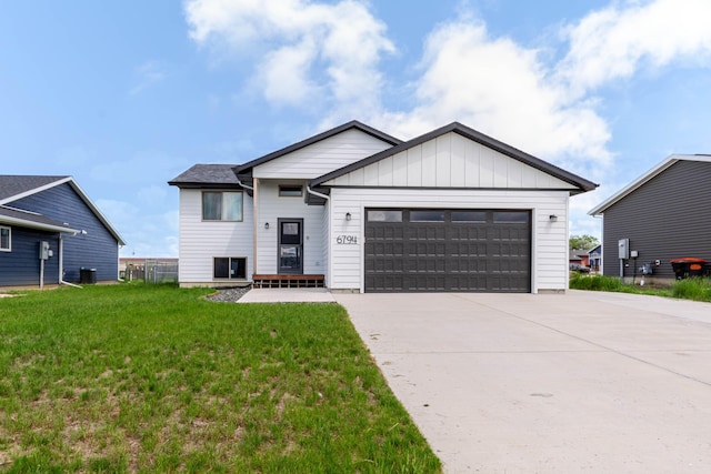 6794 Abelia St, Rapid City, SD 57703 - view of front of house featuring a garage, driveway, a front lawn, board and batten siding, and cooling unit