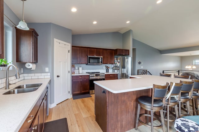 6794 Abelia St, Rapid City, SD 57703 - kitchen with appliances with stainless steel finishes, a sink, light wood-type flooring, a kitchen bar, and light countertops