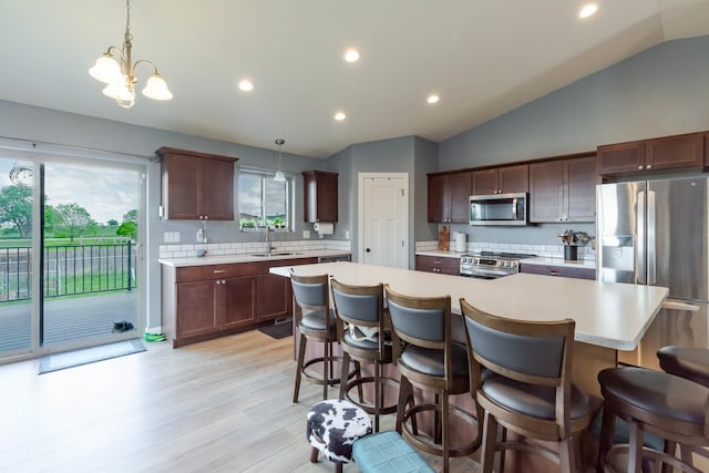 6794 Abelia St, Rapid City, SD 57703 - kitchen with stainless steel appliances, a sink, light countertops, lofted ceiling, and light wood finished floors