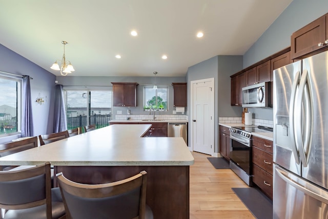 6794 Abelia St, Rapid City, SD 57703 - kitchen with appliances with stainless steel finishes, a sink, light wood-style flooring, a kitchen island, and a chandelier