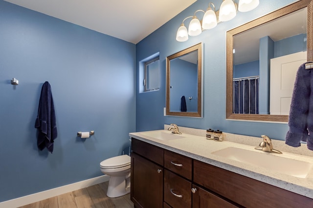 6794 Abelia St, Rapid City, SD 57703 - bathroom featuring double vanity, wood finished floors, toilet, and baseboards