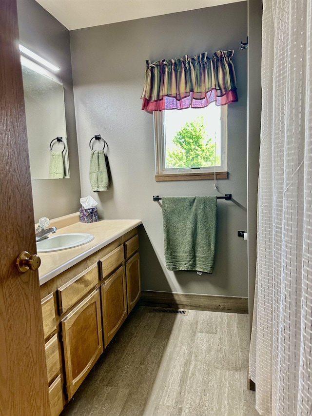 13B Statesboro Dr, Belle Fourche, SD 57717 - full bathroom with vanity, wood finished floors, baseboards, and a shower with shower curtain