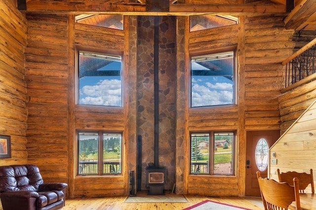 23470 Mineral Ln, Hill City, SD 57745 - living room with a wood stove, light wood-style flooring, log walls, a towering ceiling, and stairs