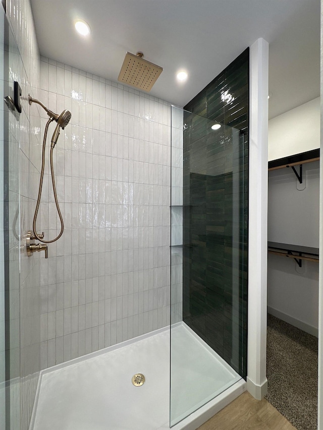 13439 Frontier Loop, Piedmont, SD 57769 - bathroom featuring tiled shower, recessed lighting, a spacious closet, wood finished floors, and baseboards