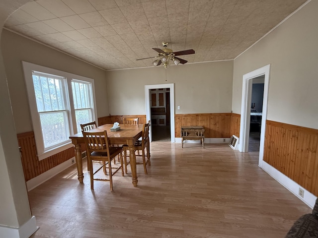 304 6th Ave, Edgemont, SD 57735 - dining space featuring a wainscoted wall, wood walls, wood finished floors, ceiling fan, and ornamental molding