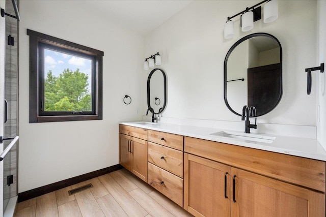 2431 Malibu Loop, Sturgis, SD 57785 - bathroom with double vanity, wood finished floors, baseboards, and a shower with door