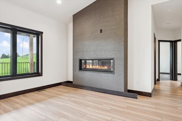 2431 Malibu Loop, Sturgis, SD 57785 - unfurnished living room featuring baseboards, wood finished floors, a glass covered fireplace, and recessed lighting