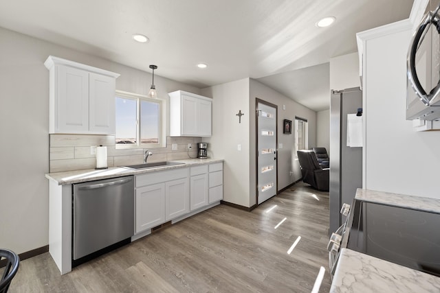 24005 Bridle Ridge Ct, Rapid City, SD 57701 - kitchen with stainless steel appliances, light wood finished floors, white cabinets, decorative backsplash, and recessed lighting