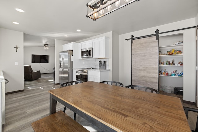 24005 Bridle Ridge Ct, Rapid City, SD 57701 - dining area featuring a barn door, light wood finished floors, a ceiling fan, and recessed lighting