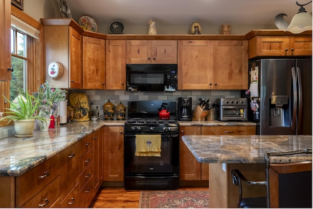 1335 E Woodland Dr, Spearfish, SD 57783 - kitchen featuring black appliances, tasteful backsplash, brown cabinets, and stone countertops