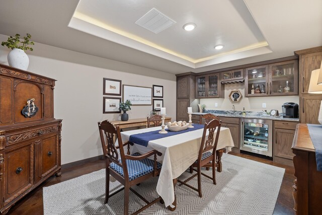 6315 Dunsmore Rd, Rapid City, SD 57702 - dining space featuring wine cooler, wet bar, a tray ceiling, dark wood-style flooring, and recessed lighting