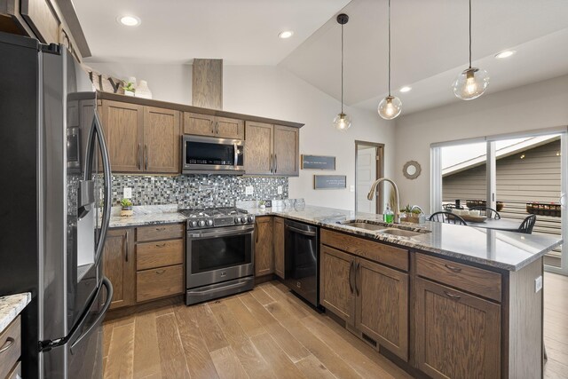 6315 Dunsmore Rd, Rapid City, SD 57702 - kitchen featuring stainless steel appliances, a peninsula, lofted ceiling, light wood finished floors, and decorative backsplash